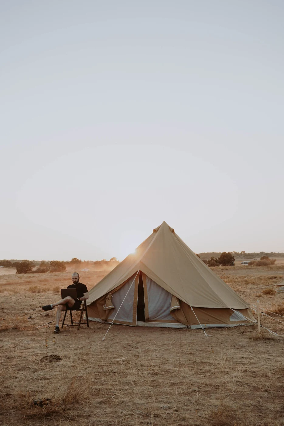 An outdoor laptop workspace beside a tent